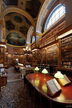 an old library with many bookshelves and lamps on the tables in front of them