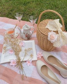 a picnic blanket with flowers, tea cups and an open book