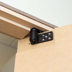 a pair of black screws are attached to the side of a wall with a wooden frame