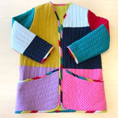 a colorful jacket with polka dots on it sitting on top of a wooden table next to a pair of scissors