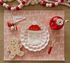 a santa clause themed table setting on a pink background