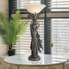 a table with a lamp on top of it next to a potted plant and window