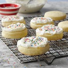 cookies with white frosting and sprinkles on a cooling rack