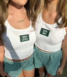 two women wearing matching white shirts and green plaid shorts with the words zeta little on them