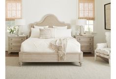 a bedroom with white furniture and zebra print pillows on the bed, along with two chairs