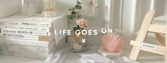 there is a vase with flowers in it next to books and a ladder that says life goes on