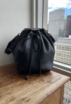 "For more handmade leather bags, purses, satchels, messengers, travel bags, holdalls, carry alls, handbags, shoulder bags, click here: http://etsy.me/1muiXbL. Large size bucket bag is made out of soft black bison leather and soft black leather strap. Its easily opens and closes with the leather drawstring, it expansionists and minimizes very easily and turns a purse into a weekender. Our bucket bag comes with an adjustable and removable leather strap, brass hardware and large hanging pocket. Mad Bison Leather, Soft Leather Handbags, Black Leather Crossbody Bag, Leather Notebook, Handbag Black, Black Leather Handbags, Leather Bucket Bag, Leather Bucket, Leather Bags Handmade