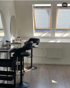 an empty salon with chairs, mirrors and stools in front of two windows on the wall