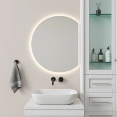 a white sink sitting under a round mirror next to a wall mounted faucet