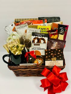 a gift basket filled with coffee, chocolates and candies next to a red bow