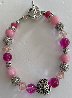 Pink crystals, pink gemstone, pink glass, silvery beads and designs with a heart shaped silvery toggle clasp.  This bracelet measures 7 3/4 inches. Adjustable Pink Beaded Bracelet With Silver Beads, Silver Beaded Crystal Bracelet For Valentine's Day, Valentine's Day Silver Beaded Crystal Bracelet, Pink Heart-shaped Jewelry With Lobster Clasp, Adjustable Pink Jewelry With Silver Beads, Adjustable Pink Crystal Bracelet With Faceted Beads, Adjustable Pink Beaded Nickel-free Bracelets, Adjustable Pink Nickel-free Beaded Bracelets, Adjustable Nickel-free Pink Beaded Bracelets