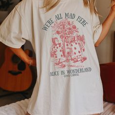 Get ready to be OBSESSED with your new Alice in Wonderland Lewis Carroll Mad Hatter shirt. It's the cutest and most trendy way to combine all those important trendy dark academia and literature shirt vibes! This is the perfect disneyworld shirt!  * Q U I C K * F A C T S * ✺  All shirts are UNISEX ✺  100%  ringspun cotton (fiber content may vary for different colors) ✺  Soft-washed, garment-dyed fabric brings extra coziness ✺  Wash and dry normally (on cool for best results) ✺  Sewn-in twill label * S I Z I N G * ✺ For an oversized fit, select two or three sizes up from your normal size ✺ Model is wearing size L  ✺ Sizing runs true to size ✺ Relaxed fit ✺ Most women find their typical size works best, since they are meant to fit a touch loose ✺ See Size guide and fit in images          * S Alice In Wonderland T Shirt, Bookish Short Sleeve Tops For Spring, Bookish Relaxed Fit Graphic Print Top, Spring Cotton T-shirt With Bookish Style, Spring Bookish Short Sleeve Tops, Bookish Short Sleeve T-shirt For Spring, Spring Bookish Style Short Sleeve T-shirt, Spring Bookish Short Sleeve T-shirt, Spring Bookish T-shirt With Letter Print