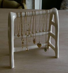 there is a white shelf with many necklaces on it and a chair in the background