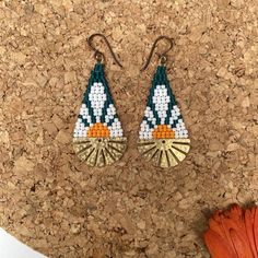 a pair of earrings sitting on top of a cork board next to a flower pot