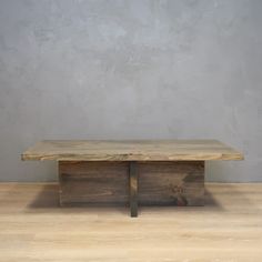 a wooden table sitting on top of a hard wood floor next to a gray wall