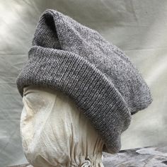 This Tubular knit hat is able to be worn a variety of ways. Can be doubled with a tapered flap hanging to one side of the head or folded completely in and turned up around the brim for 4 layers of warm wool around the ears. The pattern I have developed is based on a hat recovered from the "Machault" ship This medium we Wool Hat One Size For Outdoor, One Size Wool Hat For Outdoor, Merino Wool Hat For Cold Weather, Merino Wool Beanie Hat, Merino Wool Beanie Hat One Size, Warm Gray Wool Hat, Adjustable Knitted Wool Hat, Knitted Brimmed Bonnet For Cold Weather, Winter Curved Brim Bonnet, One Size