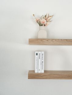 two wooden shelves with books and flowers on them