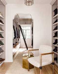 a white chair sitting next to a walk in closet filled with shoes and other items