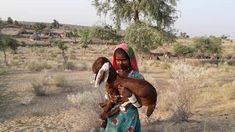 a woman holding a baby goat in the desert