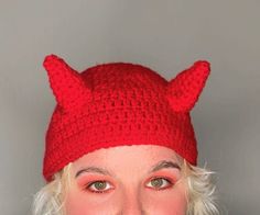 a woman wearing a red knitted devil hat with horns on her head and nose