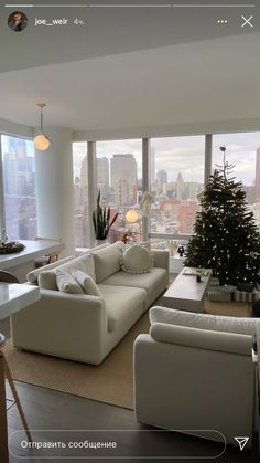 a living room filled with white furniture and a christmas tree in the middle of it