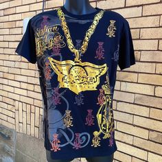 Vintage Christian Audigier Famed For Y2k Fashions Ed Hardy And Von Dutch Lines Features Gold Wings And Logo On Front And Metallic Gold Skulls And Below “All You Need Is Love” Black Shirt Size Large Black Y2k Short Sleeve Shirt, Black Short Sleeve Y2k Shirt, Black Y2k Shirt With Crew Neck, Black Y2k Crew Neck Shirt, Black Y2k Style Crew Neck Shirt, Black Y2k Shirt With Letter Print, Black Y2k Top With Sublimation Print, Black Y2k Tops With Logo Print, Y2k Black Tops With Logo Print