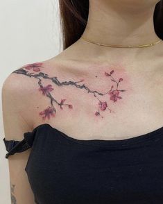 a woman with tattoos on her chest is looking at the camera and has pink flowers