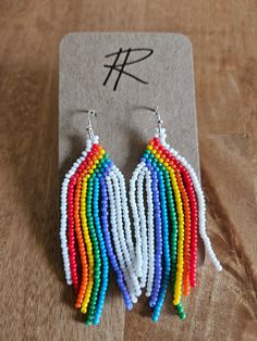 a pair of multicolored beaded earrings sitting on top of a wooden table