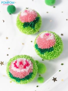 three green, pink and white balls with sprinkles on them sitting on a table