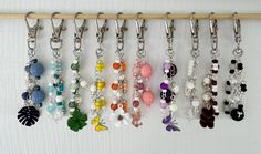 a row of key chains hanging from a wall next to a wooden stick with beads and charms on it