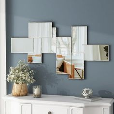 a white dresser topped with lots of mirrors next to a vase filled with flowers on top of it