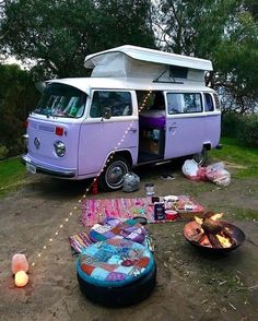 a camper van parked in the middle of a field next to a fire pit