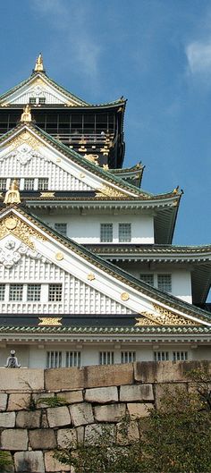 a white and gold building sitting on top of a stone wall under a blue sky