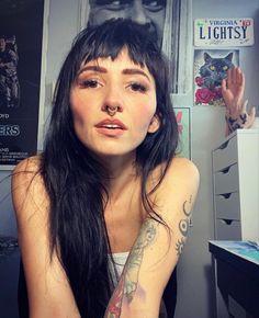 a woman with long black hair sitting in front of a refrigerator covered in magnets