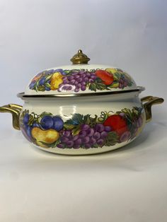 a casserole dish with fruit painted on the side and gold trimmings