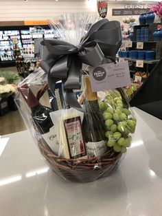 a basket filled with wine, cheese and crackers on top of a counter in a store