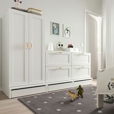 a baby's room with white furniture and toys on the floor in front of it