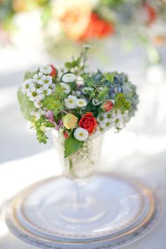 a vase filled with lots of flowers sitting on top of a white and gold plate