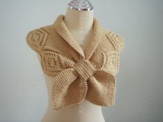 a white mannequin wearing a beige sweater with a bow on it's neck