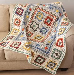 a couch with a crocheted blanket on top of it next to a wooden floor