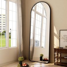 a large mirror sitting on top of a wooden floor next to a table and window