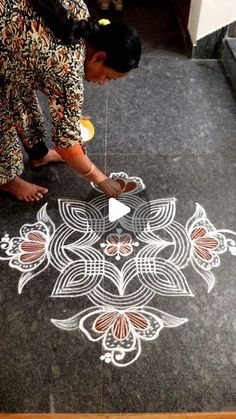 a woman is drawing on the ground with chalk