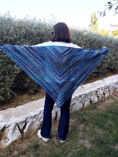 a woman is standing outside with a blue shawl