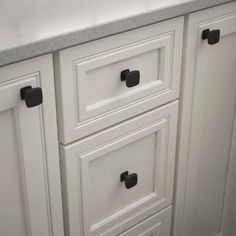 a kitchen with white cabinets and black handles