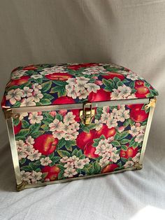 an ornately decorated box is sitting on a white sheeted surface with flowers and leaves