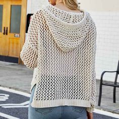 a woman is walking down the street wearing a white sweater and jeans with her back turned to the camera