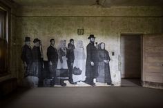 an old photo of people standing in front of a wall with the same image on it