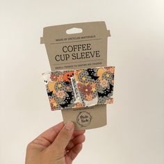 a hand holding up a package of coffee cup sleeves