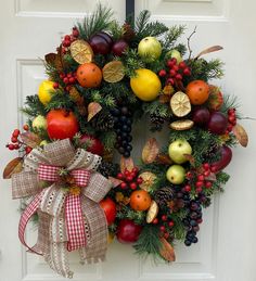 a wreath with fruits and berries hanging on the front door