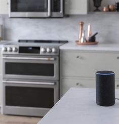 an amazon echo sitting on a kitchen counter next to a stove top oven and microwave